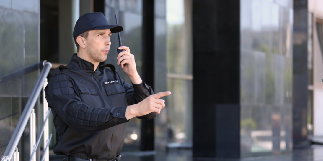 Male security guard using portable radio transmitter outdoors
